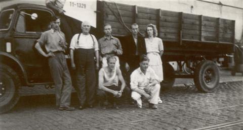 Thuiskomst 's avonds aan de Brasserie Nationale. Iedereen is hondsmoe maar voldaan. V.l.n.r.: Jan Sevenants (boven op de camion, er moest tijdens de rit altijd iemand het toestel vasthouden), Fernand Van Eylen, Charel Wolfs (de café uitbater), Rik Verbeeck, Marcel Sempels met zijn vrouw. Gehurkt: Frans Vranckx, Pol Vandermeulen. (17.08.1947)